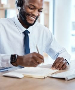 Customer service, consulting notebook and black man writing telemarketing summary for contact us CRM. Call center communication, e commerce telecom or information technology consultant on microphone.